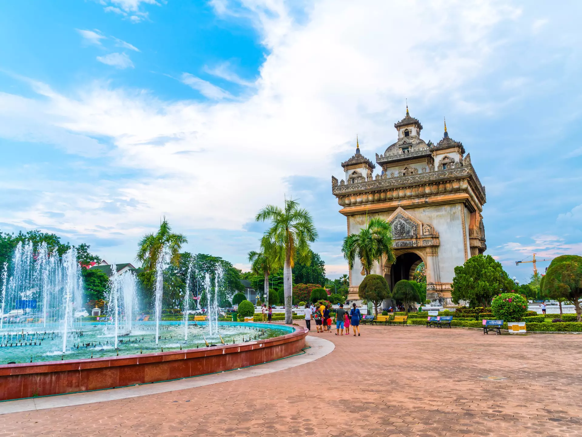 A concrete monument and archway near fountains in a garden