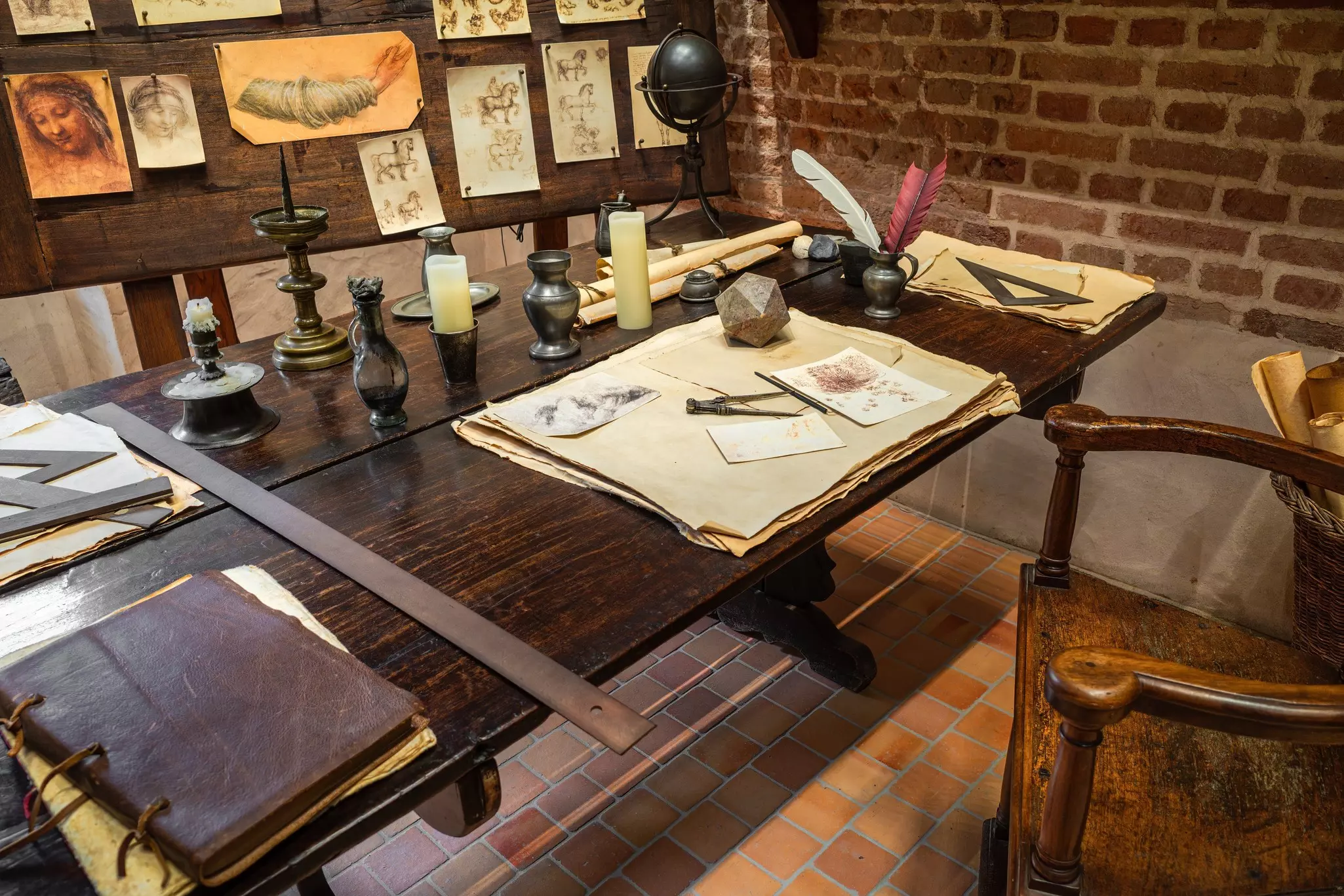 Drawings, antique writing implements and other objects are displayed on an old-fashioned desk.