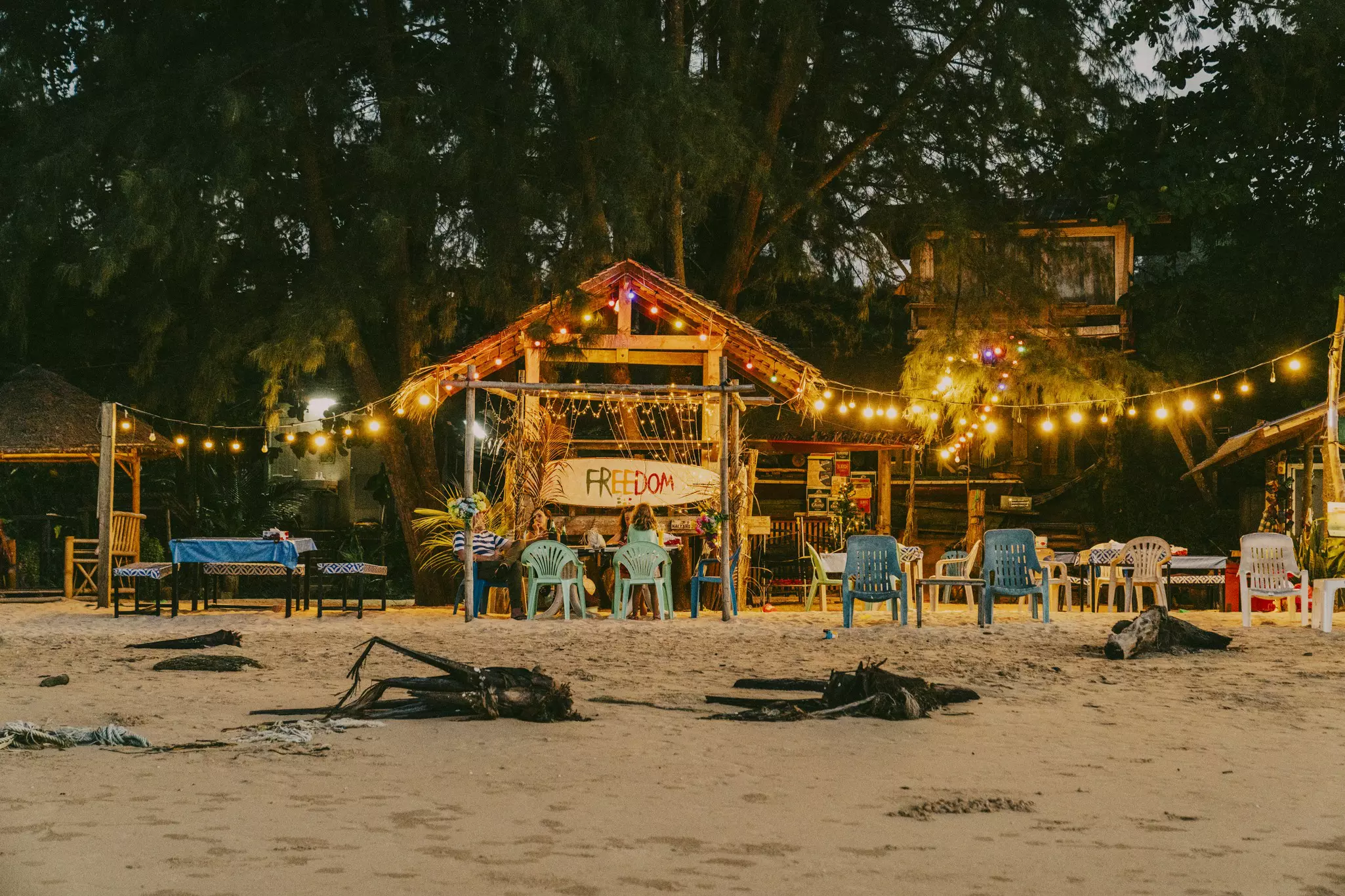 A beachside bar lit up by string lights in the evening.