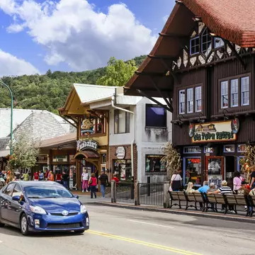 People walking around Main Street in downtown Gatlinburg Tennessee, USA. The street has an old-world feel to it, with heritage buildings, where people eat and drink outside.