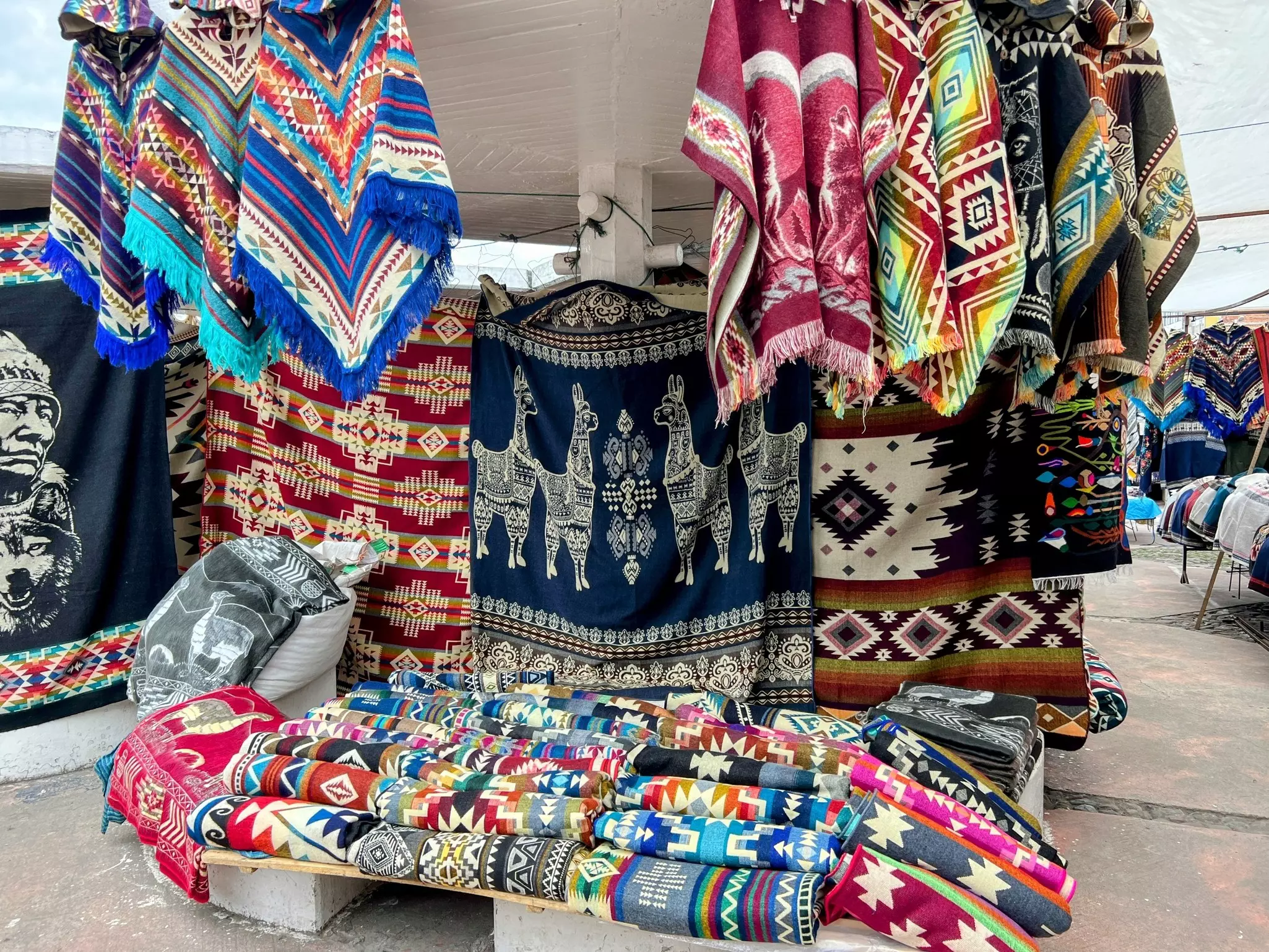 Views of the colorful indigenous market which includes handmade items like ponchos, sweaters, and shawls.