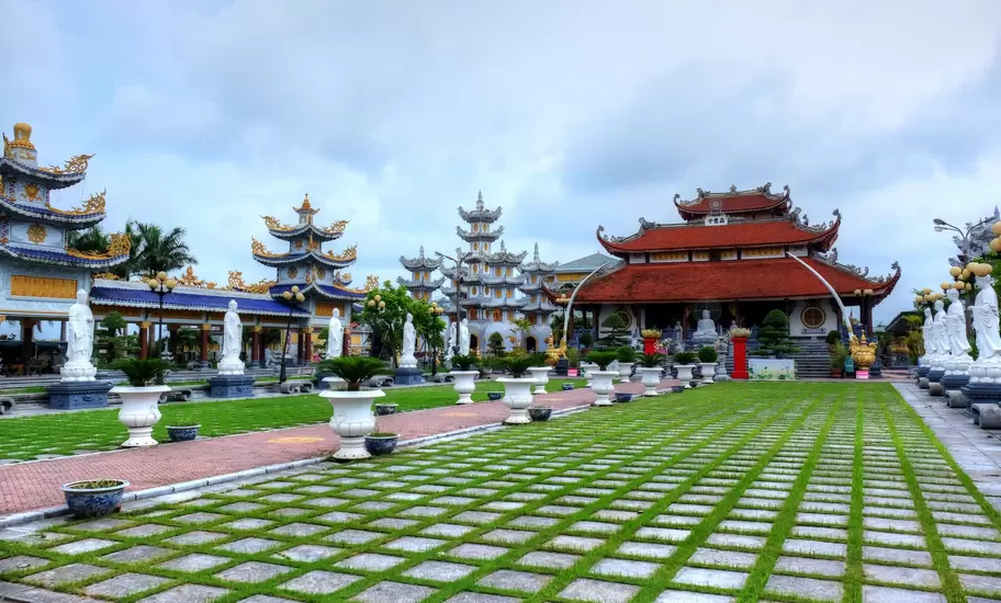 Buddhist pagoda complex in northern Vietnam with a red-roofed main hall, tiered towers and rows of white Quan Am statues