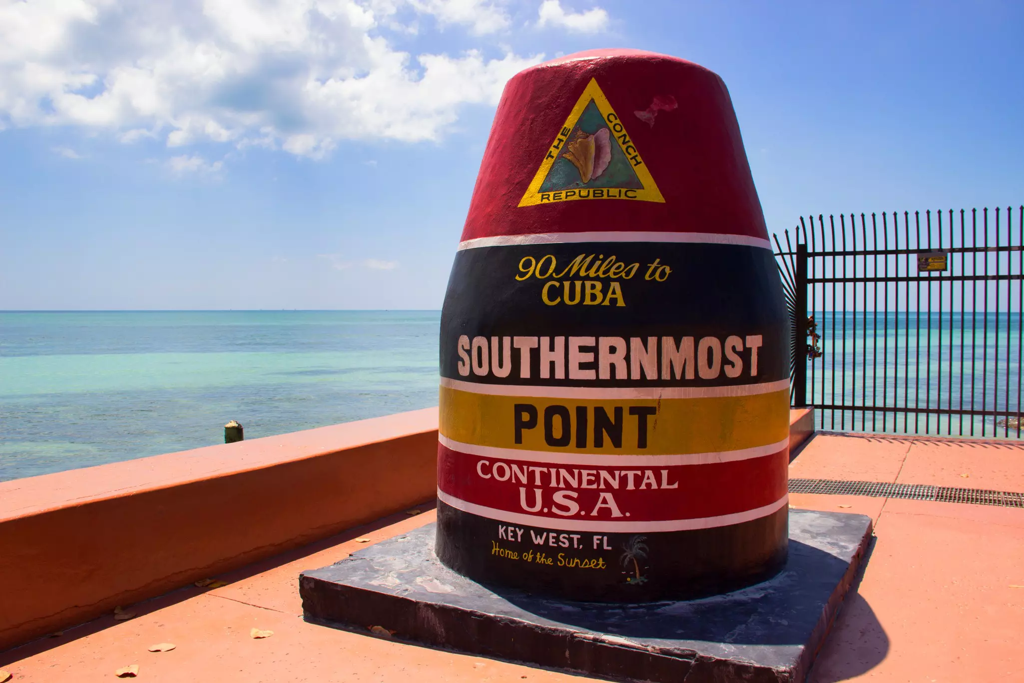 A colorful buoy that says "90 Miles to Cuba. Southernmost Point Continental U.S.A. Key West, FL. Home of the Sunset"