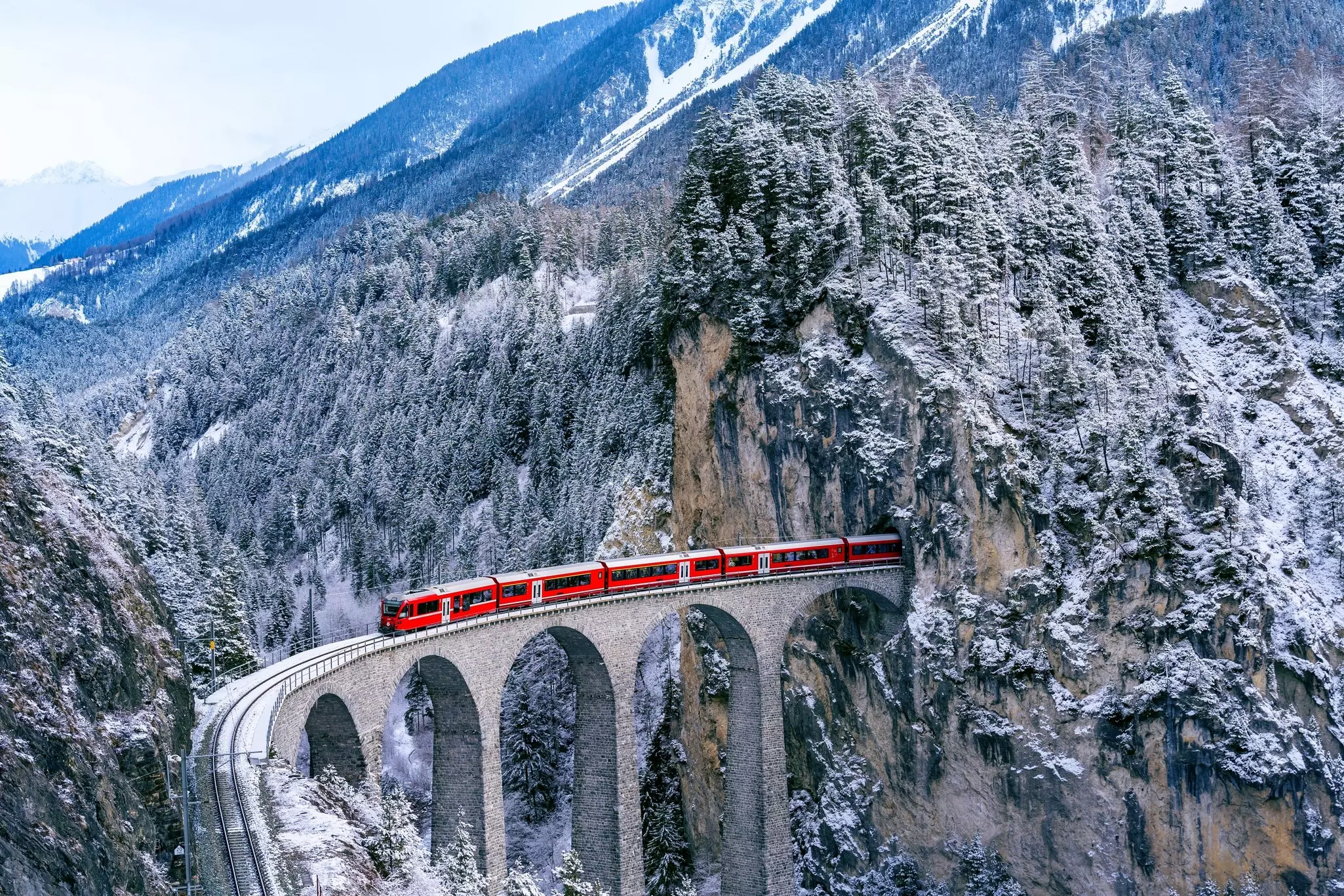 The red Glacier Express train crosses the Landwasser Viaduct in Switzerland.