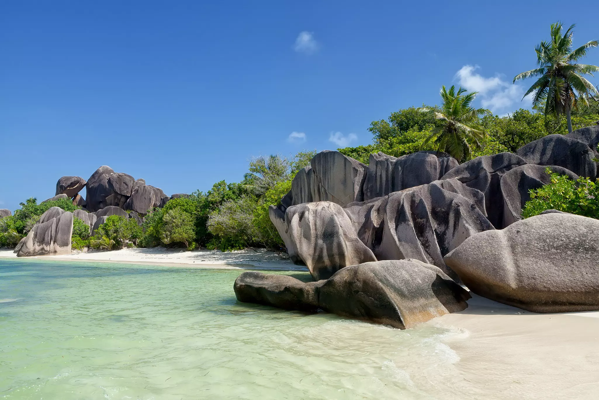 Wide shot of granite rocks with clear ocean water in the foreground.