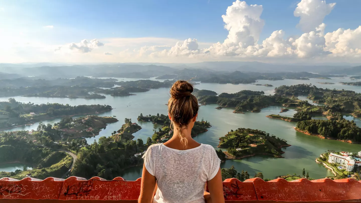 A girl seen from behind, looking out over Guatape and the expansive lake system.