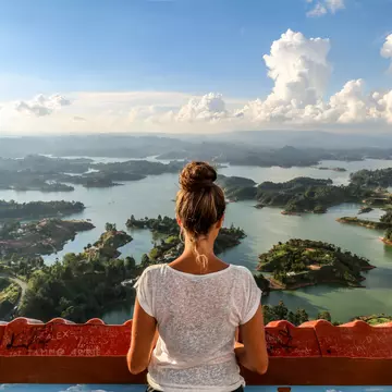 A girl seen from behind, looking out over Guatape and the expansive lake system.