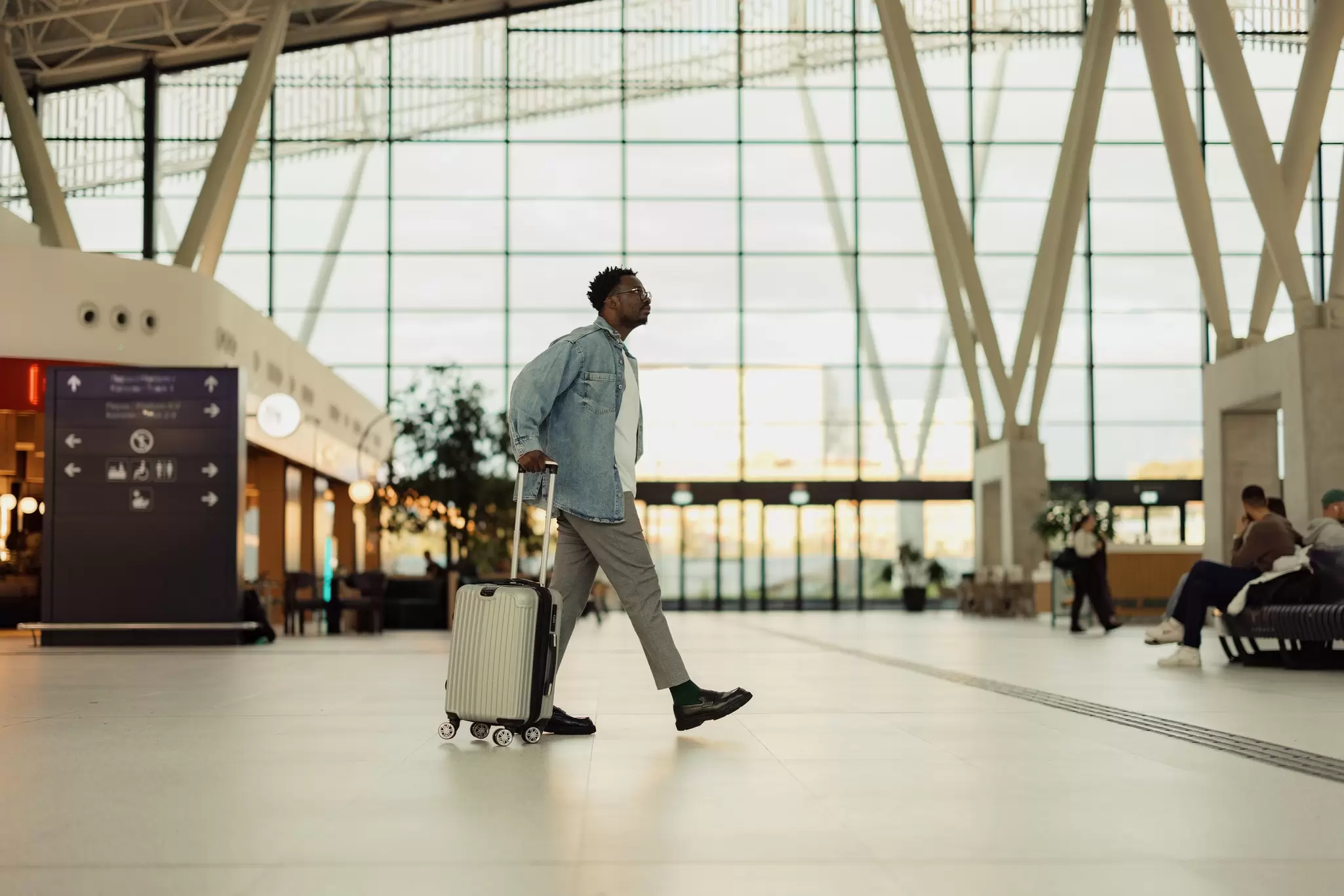 Man Walking with Suitcase in Modern Airport Terminal