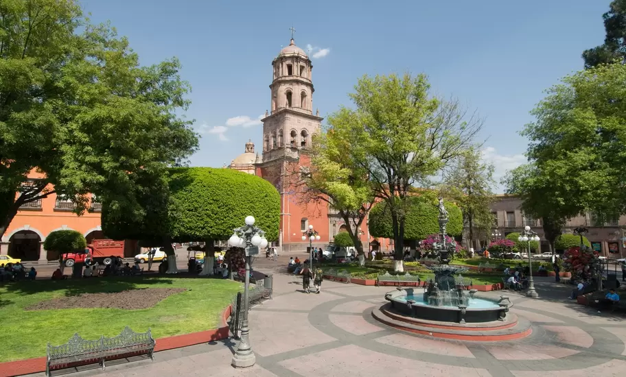 Jardín Zenea fountain, clipped trees and benches below the domed bell tower of Templo de San Francisco, Querétaro, Mexico