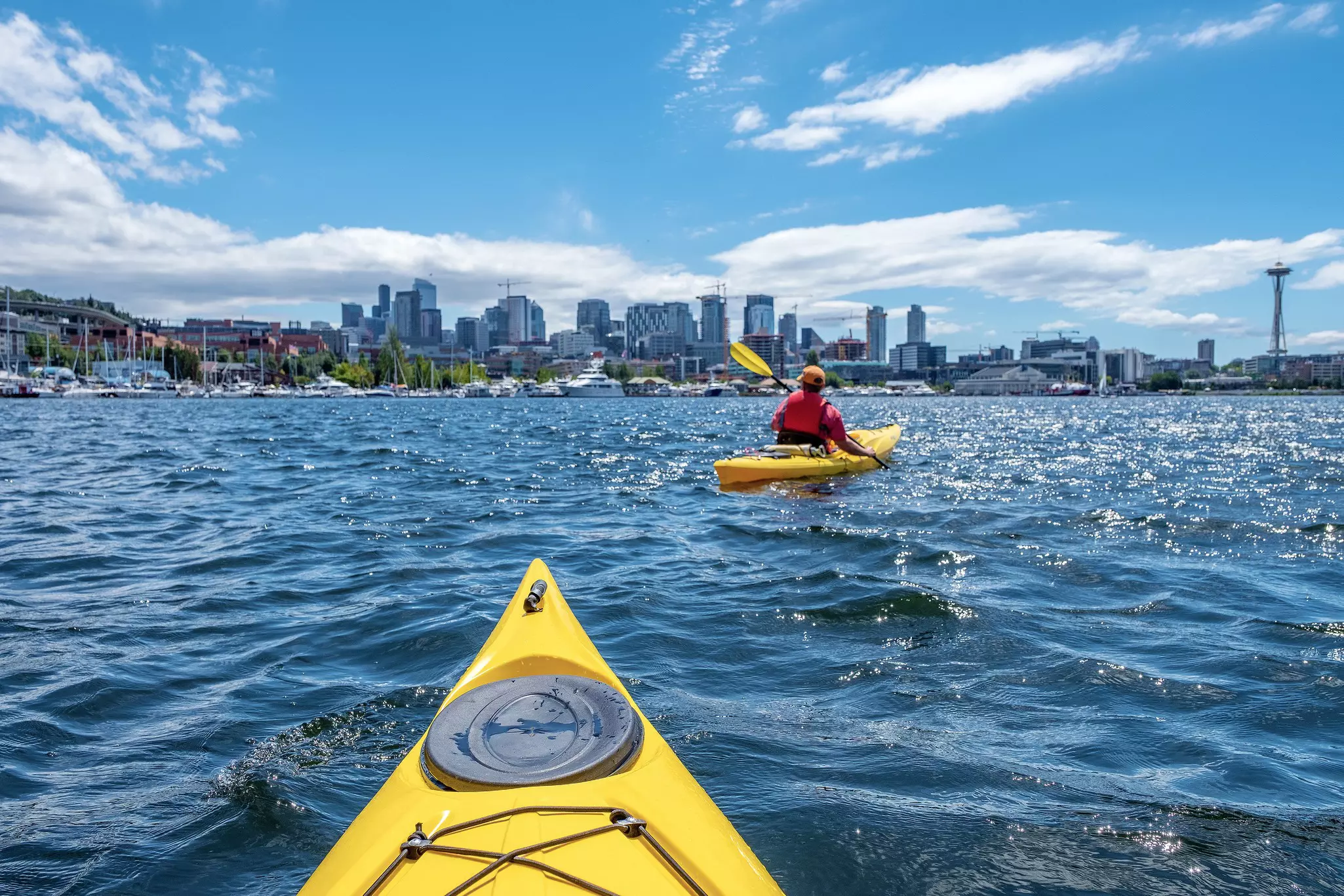 A person in a yellow kayak at Lake Union in Seattle, Washington; the city skyline is on the horizon.