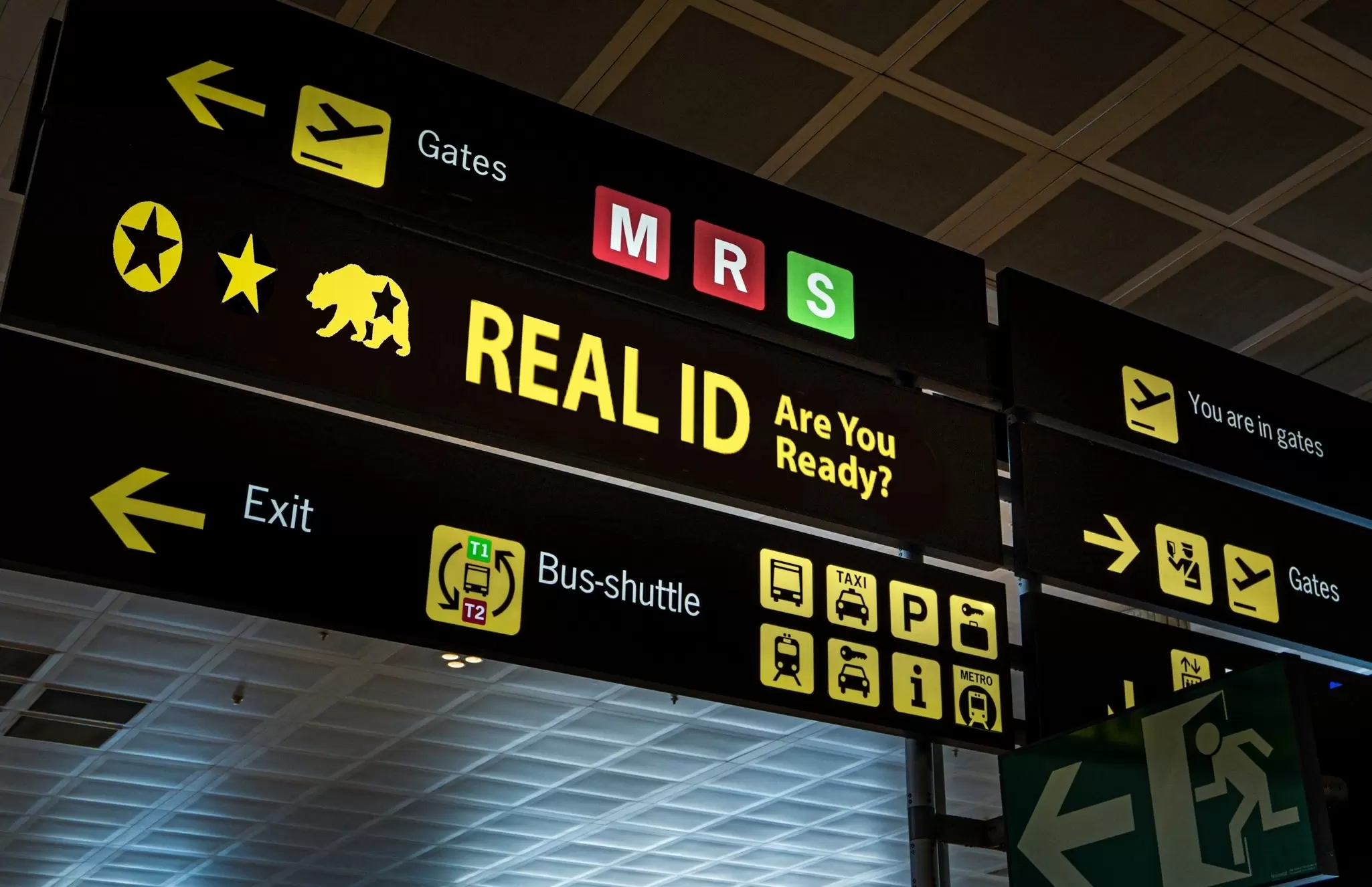 Illuminated airport signs reminding passengers about REAL ID at an airport in the US.