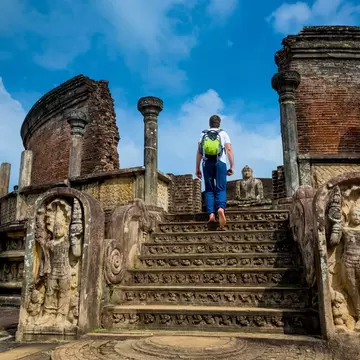 A barefoot visitor walks up steps at an ancient temple in Sri Lanka.