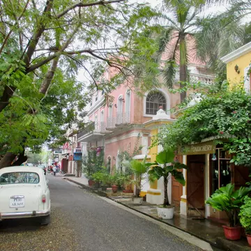 Two-story pastel-colored buildings on a tree-lined street.