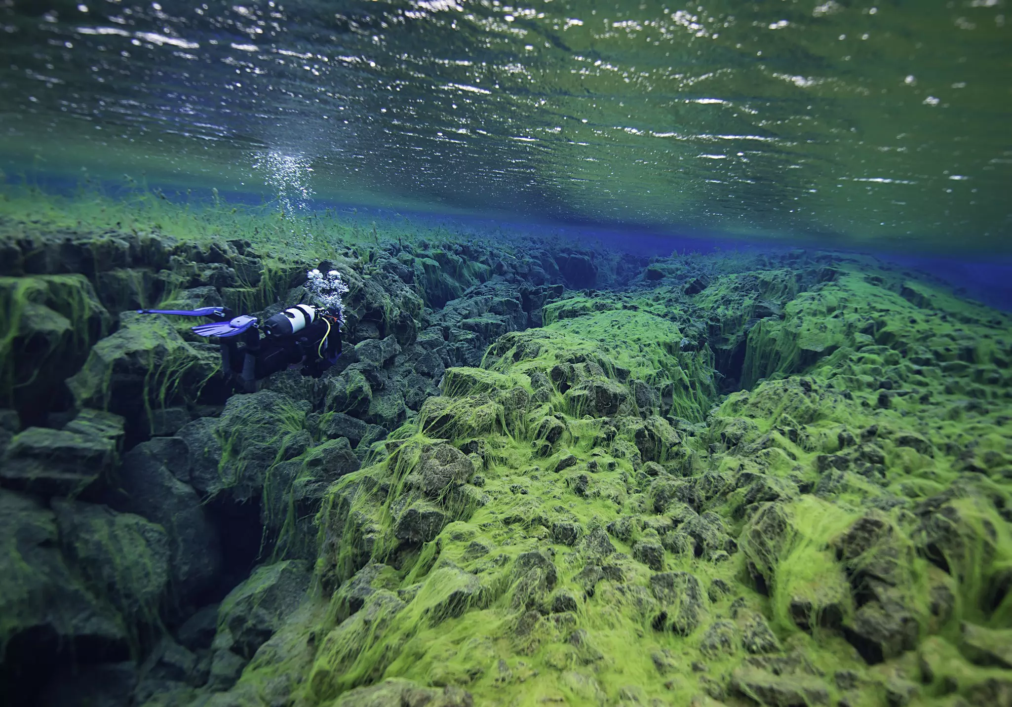 Scuba diver exploring cracks in rocks underwater