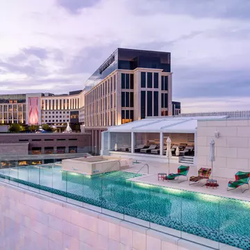 A rooftop infinity pool with sunloungers on a small terrace.