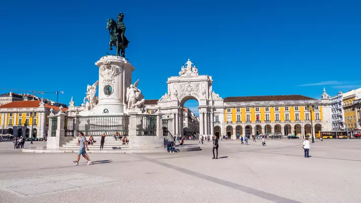 A large city square with statues and a huge ornamental archway