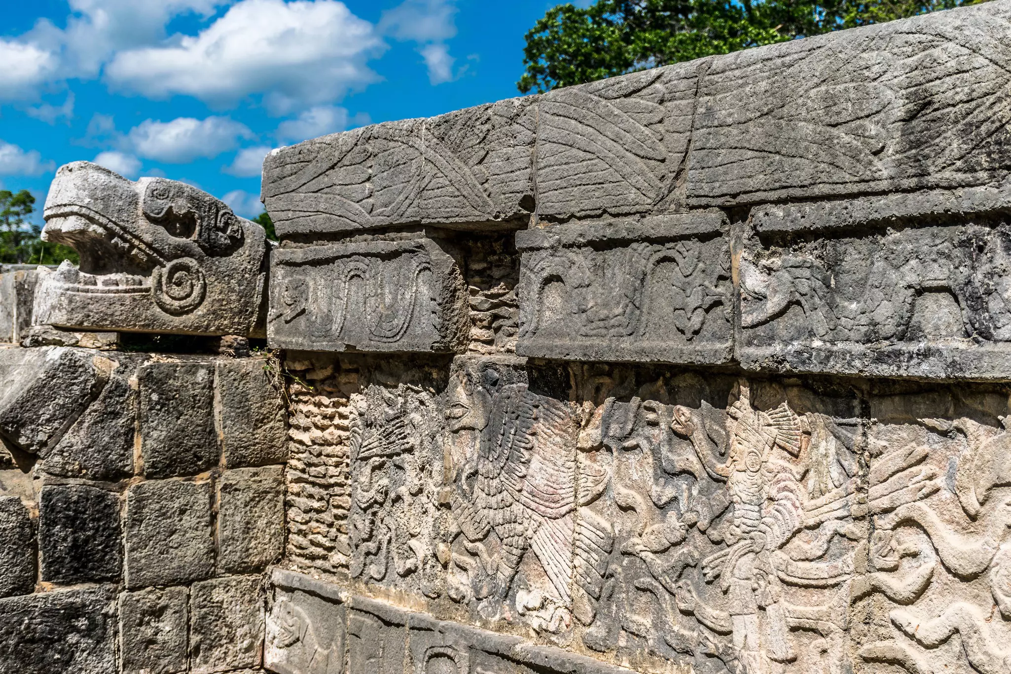 Carvings on an ancient exterior wall showing figures, creatures and serpents