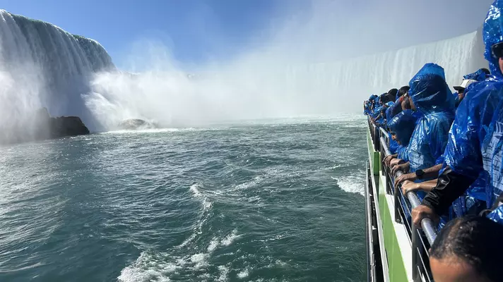 Tourists in blue ponchos splashed by the mist from the waterfall. 