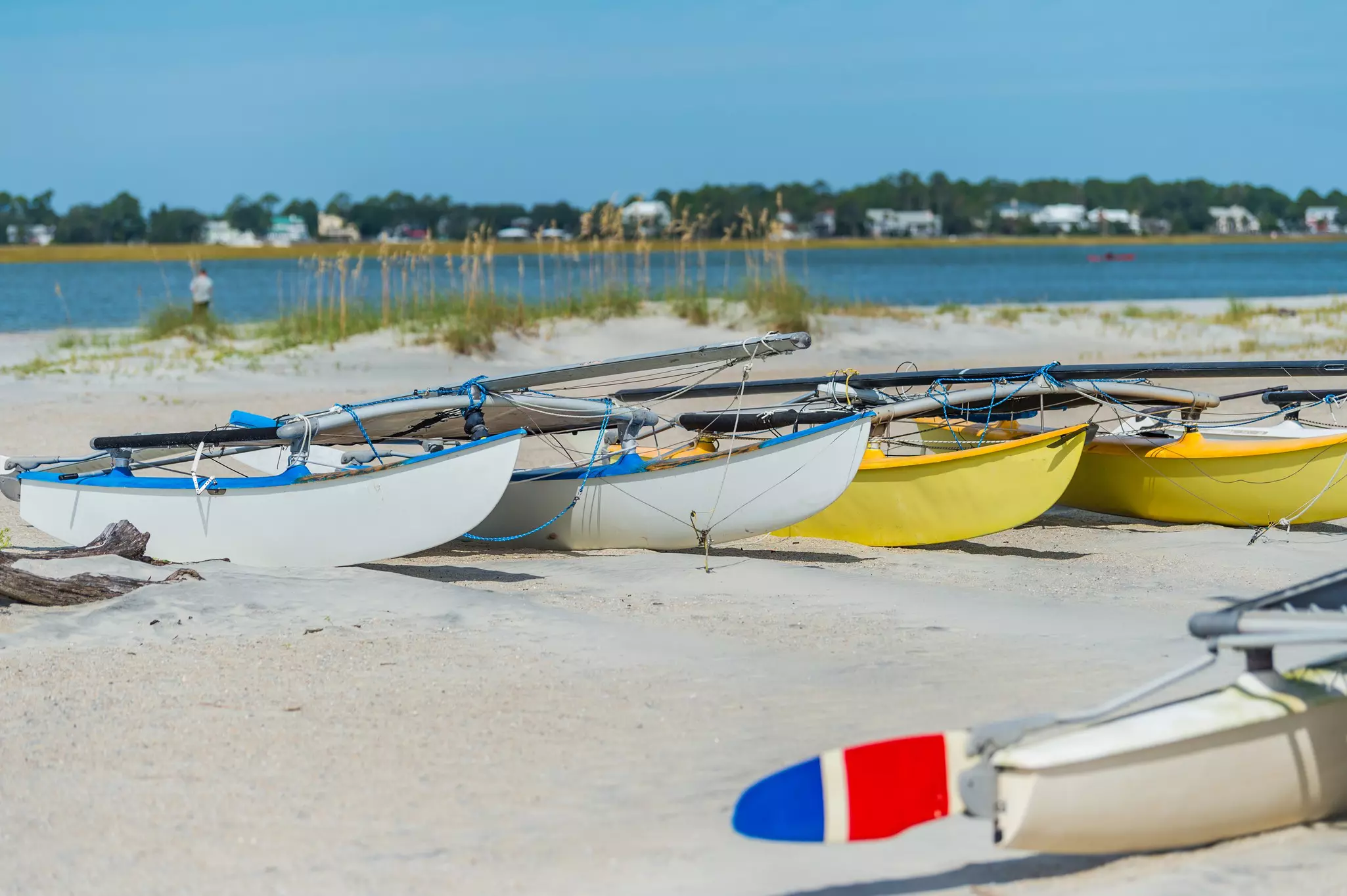 Single sailboats on white sand.