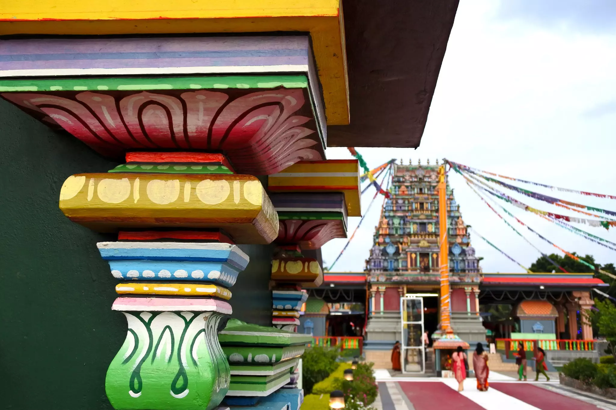A colorful column painted with exaggerated patterns within a Hindu temple complex.