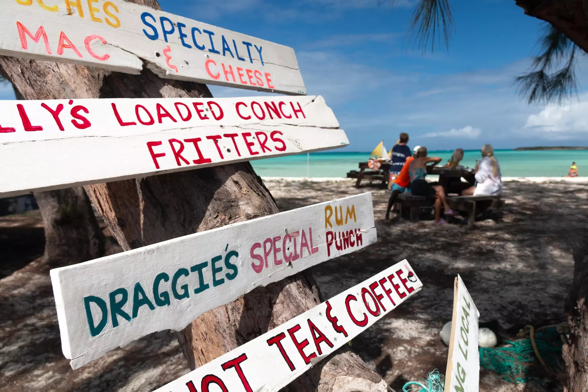 Tourists eat their lunch at a picnic table on Bambarra beach, a popular beach on the island of Middle Caicos home to colourfully-painted signs.