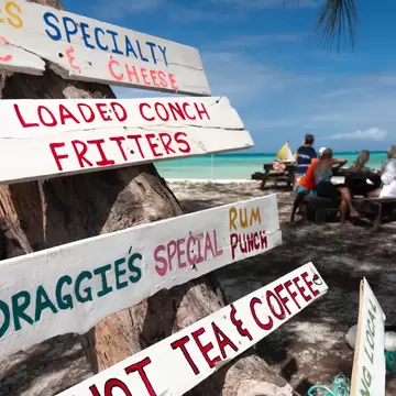 Tourists eat their lunch at a picnic table on Bambarra beach, a popular beach on the island of Middle Caicos home to colourfully-painted signs.