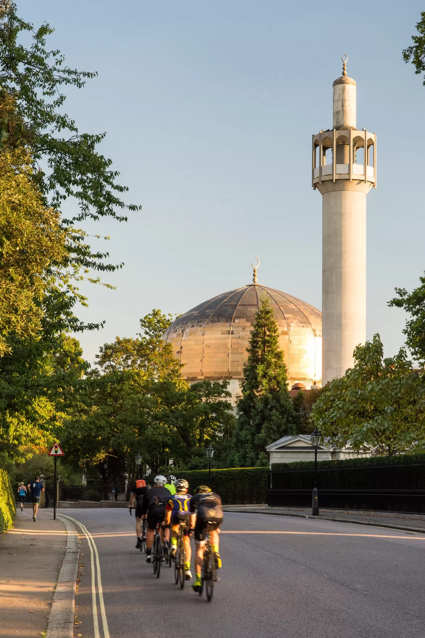 Cyclists pass the London Central Mosque on Regents Park's Outer Circle Road in London, UK.