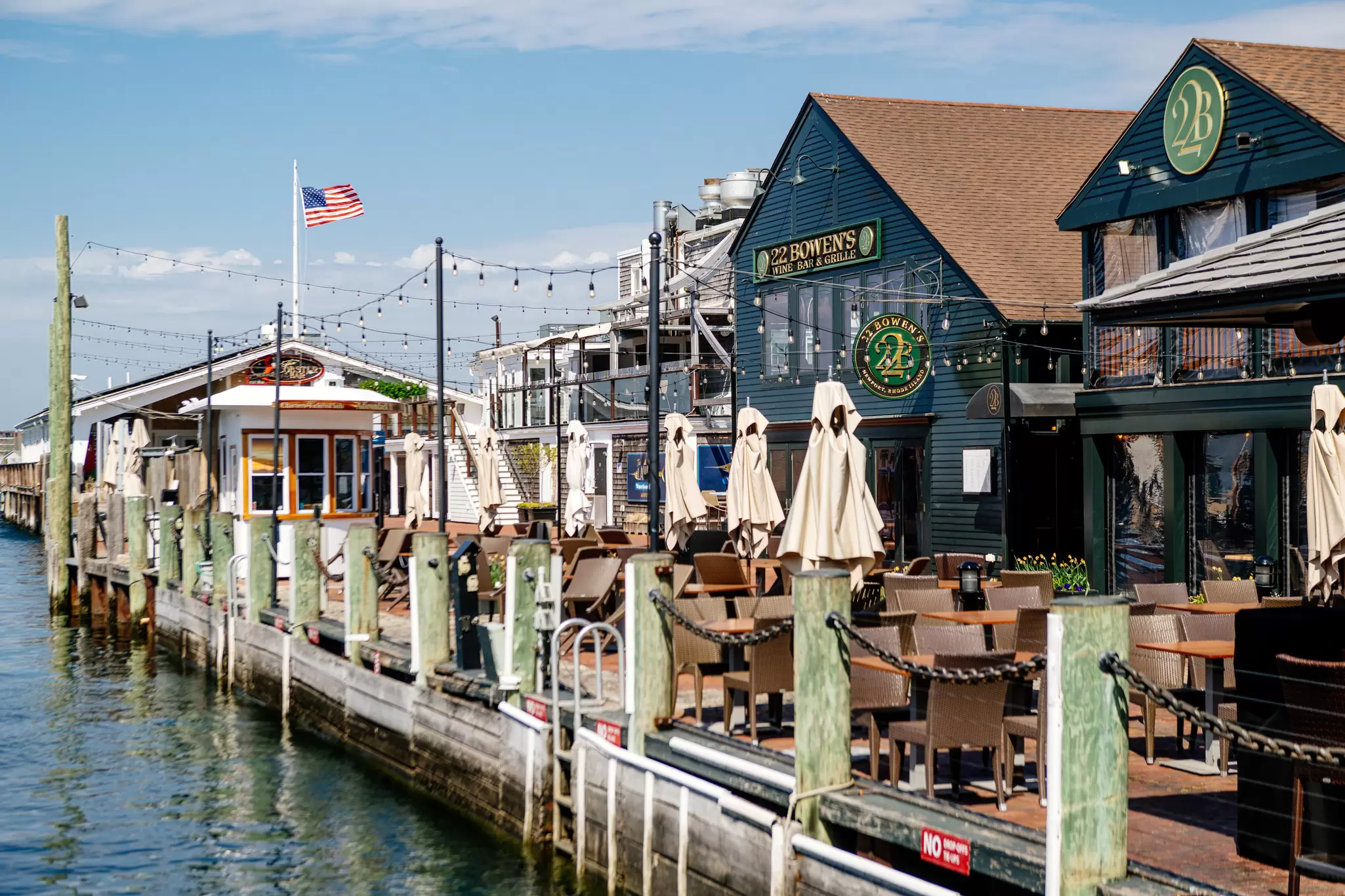 Restaurants with outdoor seating areas along a wharf on a sunny day in Rhode Island
