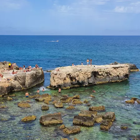 Syracuse, Italy  - JUNE 1, 2024: Spiaggia Diana nel Forte, a rocky beach with all amenities, super crowded. The water is crystal clear, making this place ideal to enjoy swimming., License Type: media, Download Time: 2025-10-09T20:04:36.000Z, User: LP_YKhanna, Editorial: true, purchase_order: 65050 - Digital Destinations and Articles, job: Lonely Planet, client: App Content, other: Yuvraj Khanna