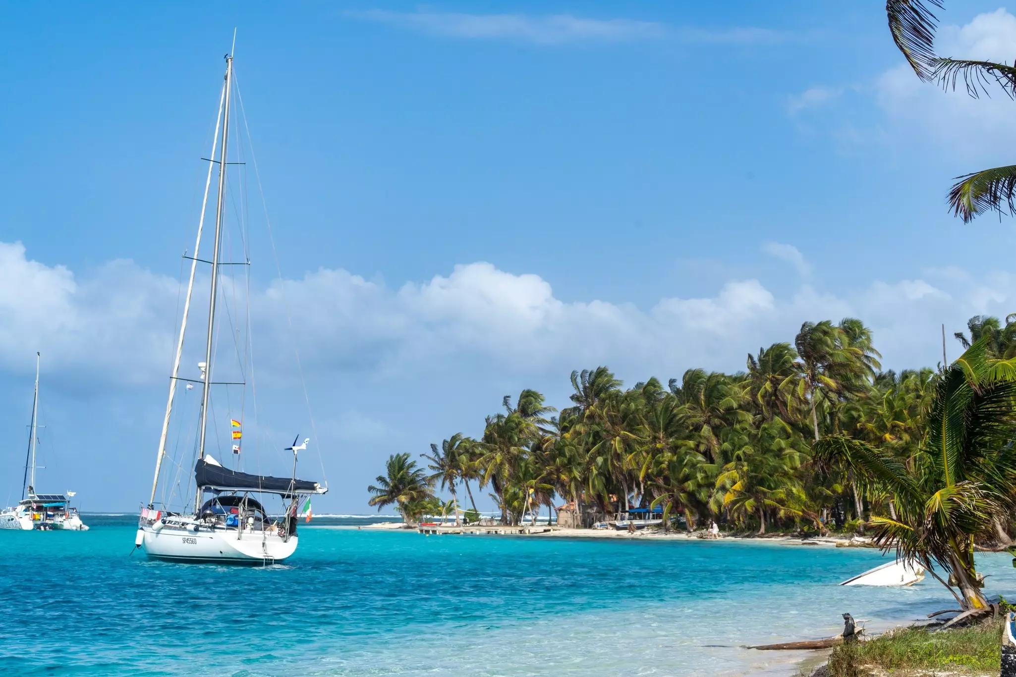 Two sailboats off an island of palm trees in Panama.