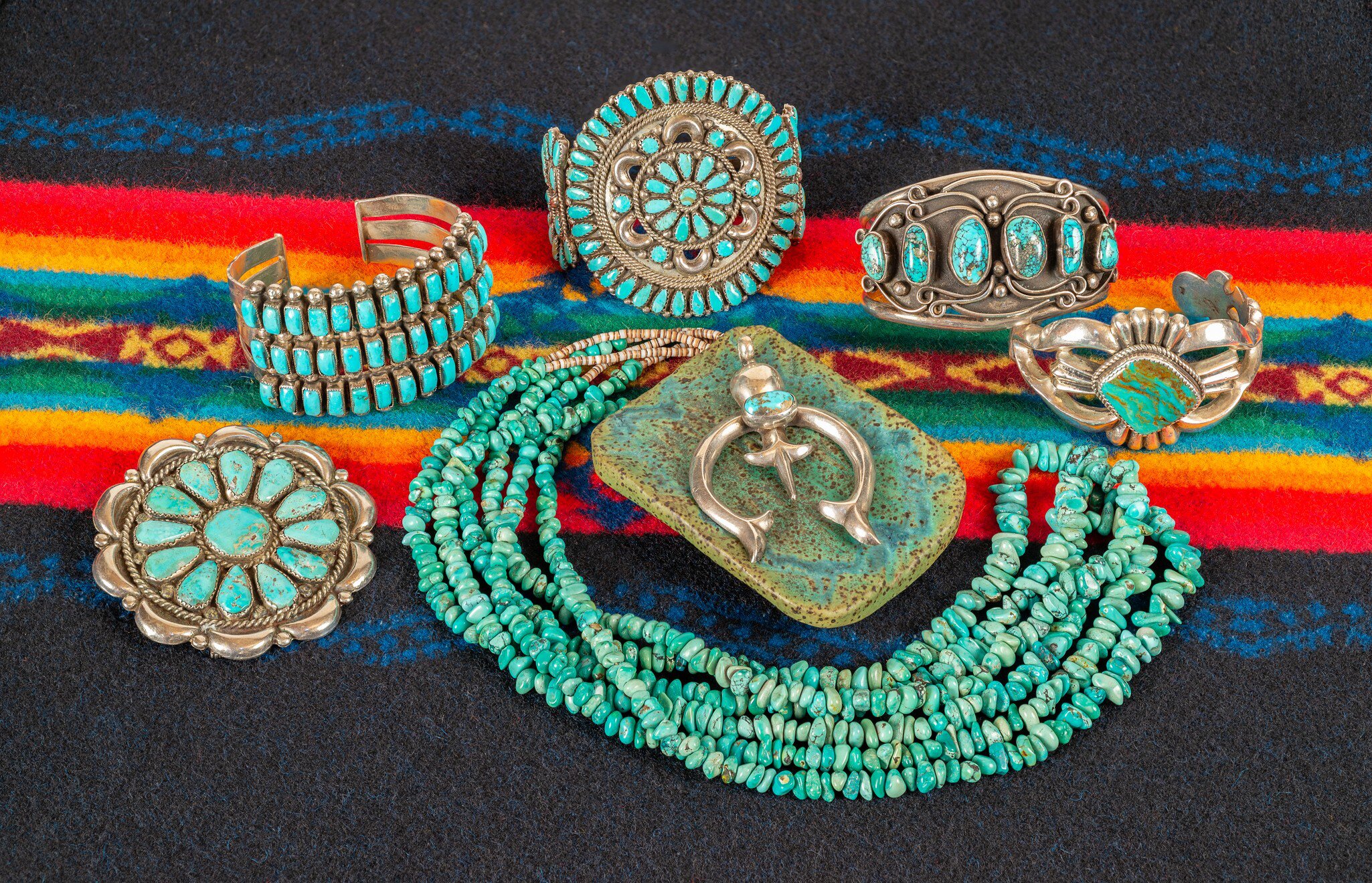 Collection of turquoise and sterling silver jewelry on a colorful textile background