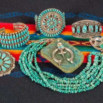Collection of turquoise and sterling silver jewelry on a colorful textile background
