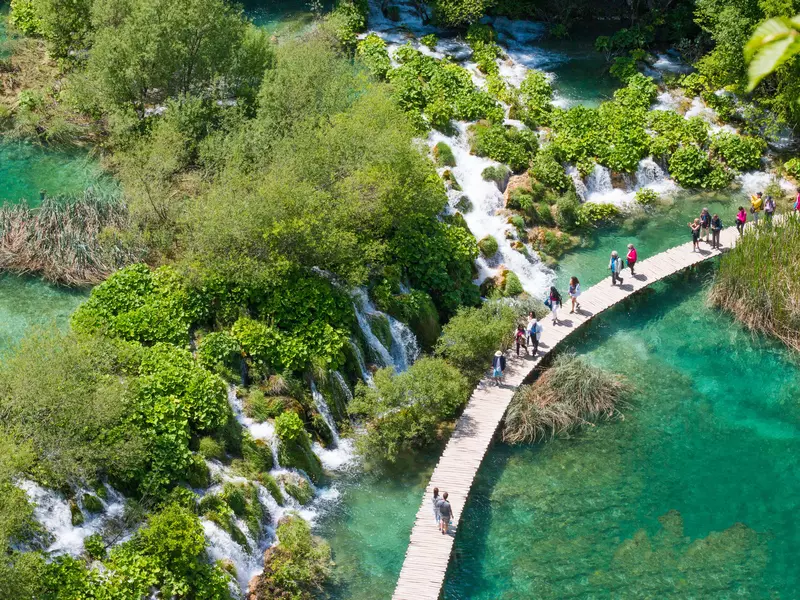 People walk over a lake via a wooden walkway