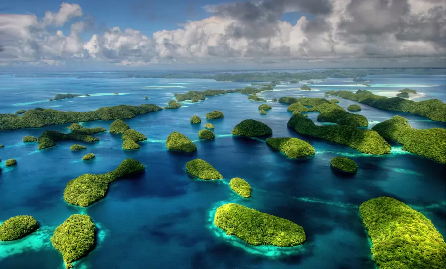Aerial view of Palau's Rock Islands, dozens of green forested islets in deep blue and turquoise lagoon water