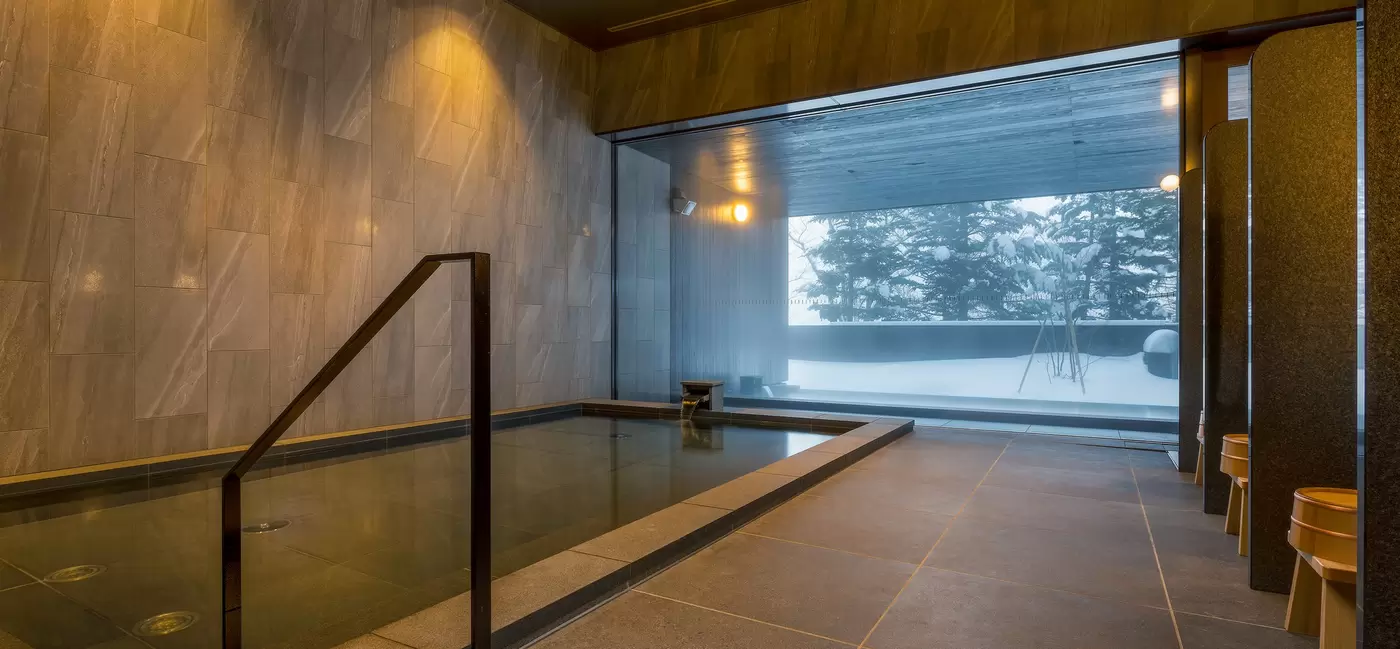 A small room with a rectangular pool and large windows: the onsen at Higashiyama Niseko Village, a Ritz-Carlton Reserve, Japan