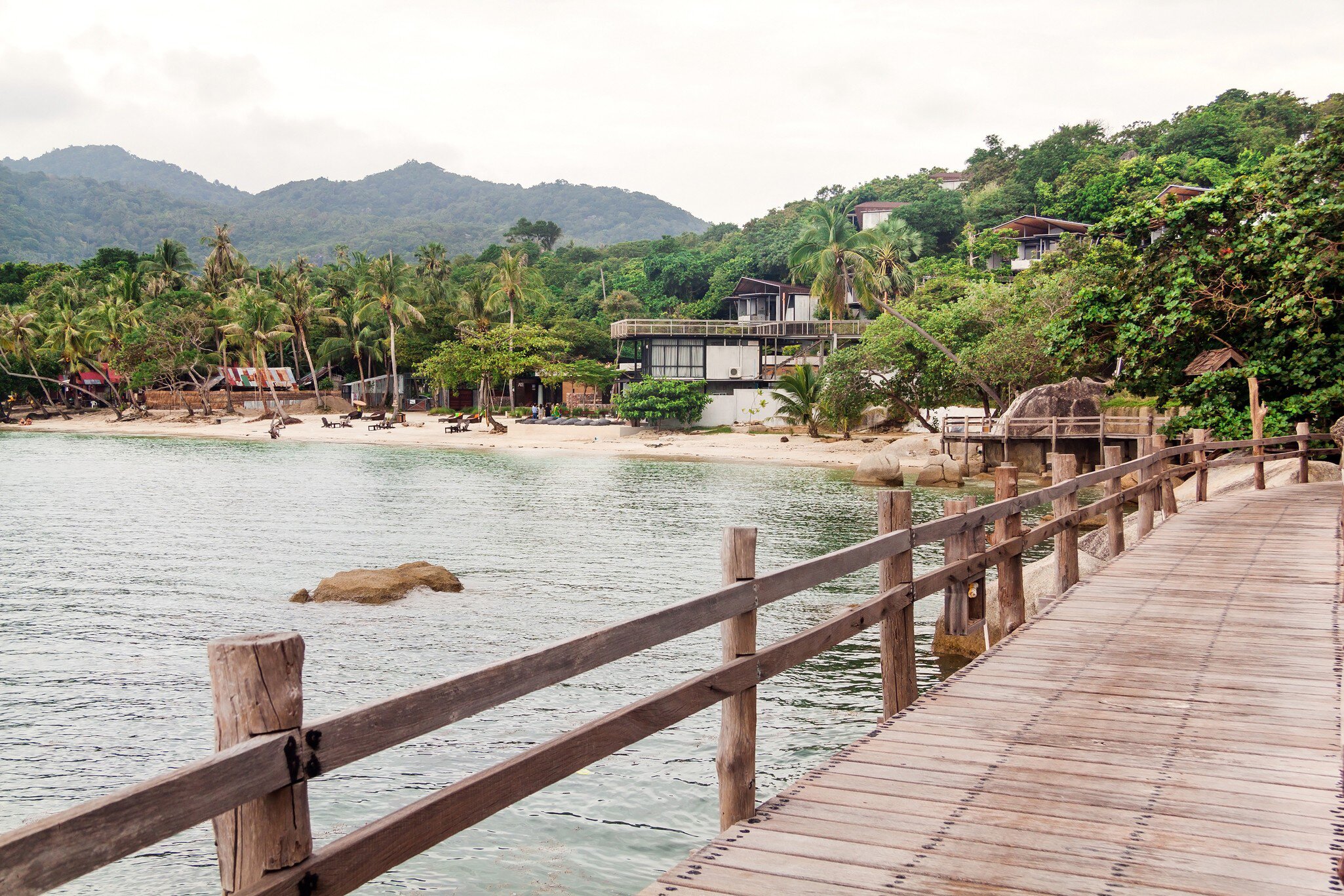 Boardwalk and pier on Haad Leela beach in Koh Pha-Ngan, Thailand. Mountains and hills in background. 