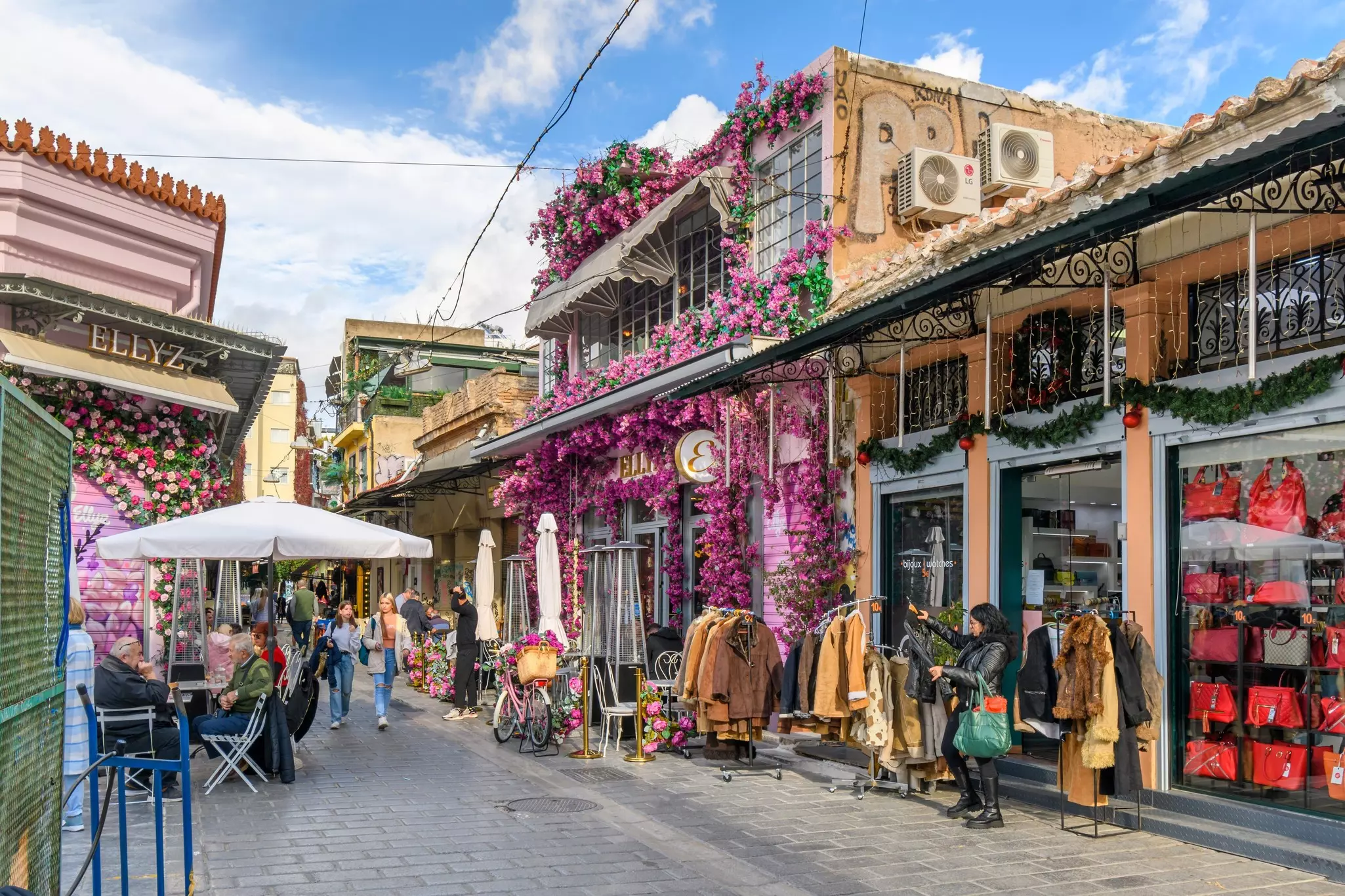 A colorfully decorated shop and sidewalk cafe with pink and magenta flowers near the Monastiraki flea market in Athens, Greece