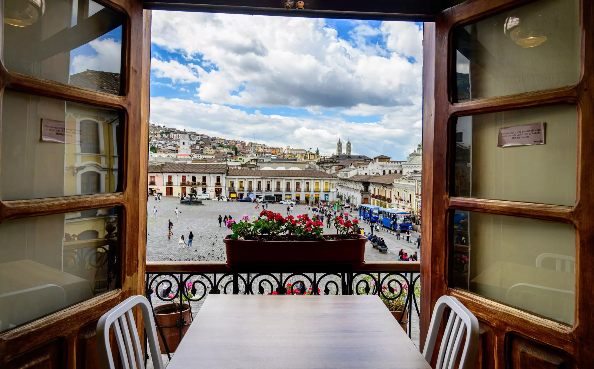 A table in a restaurant is in front of windows opening on to a view of a historic square.
