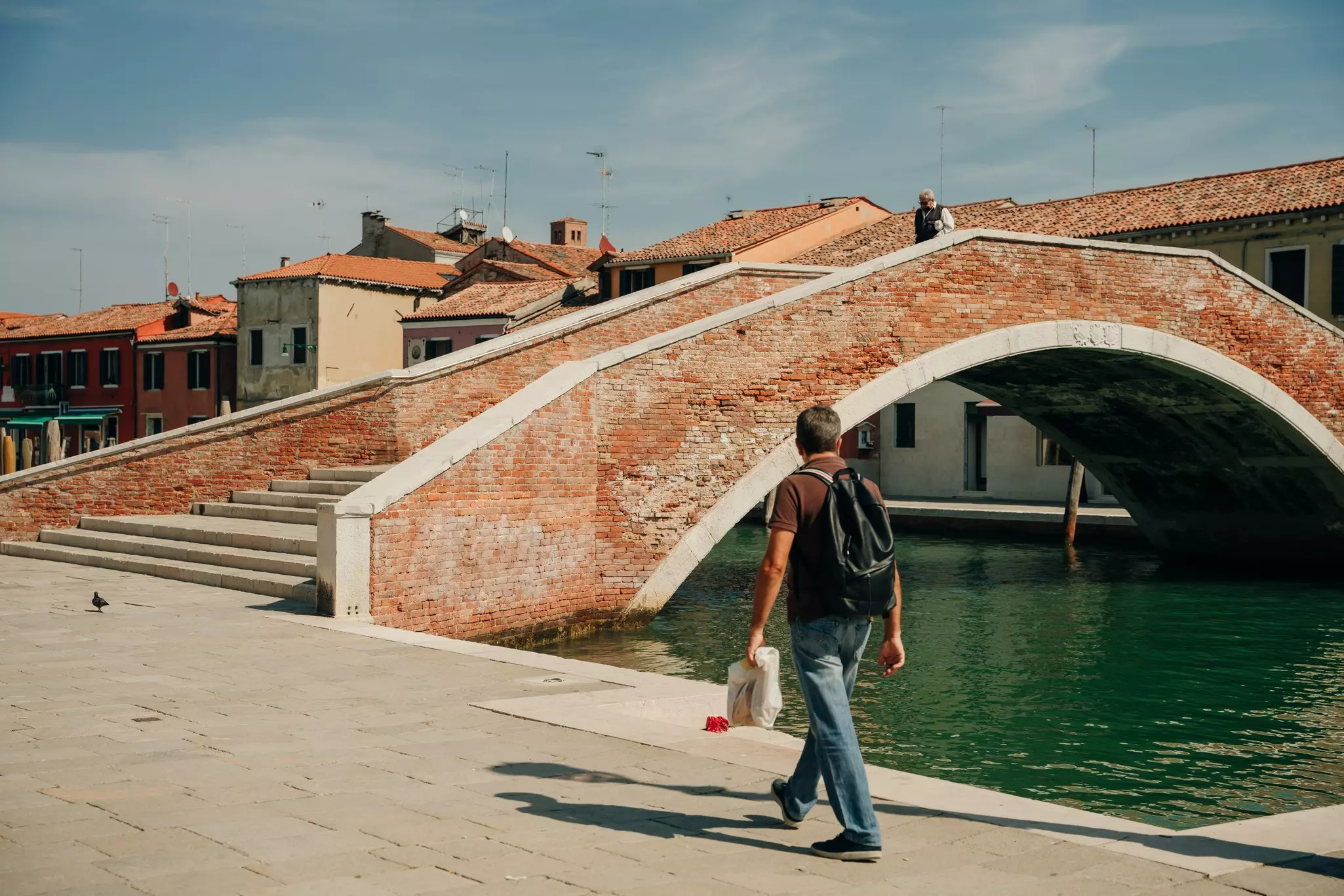 Man walking along canal in Murano island, Venice
