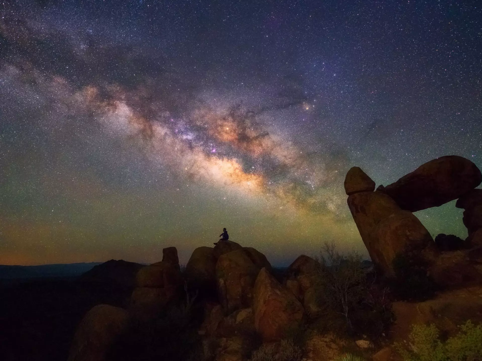 Human observing Milky way at Balanced Rock, Big Bend National park, Texas USA.