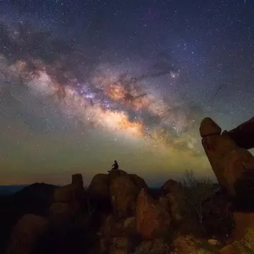 Human observing Milky way at Balanced Rock, Big Bend National park, Texas USA.