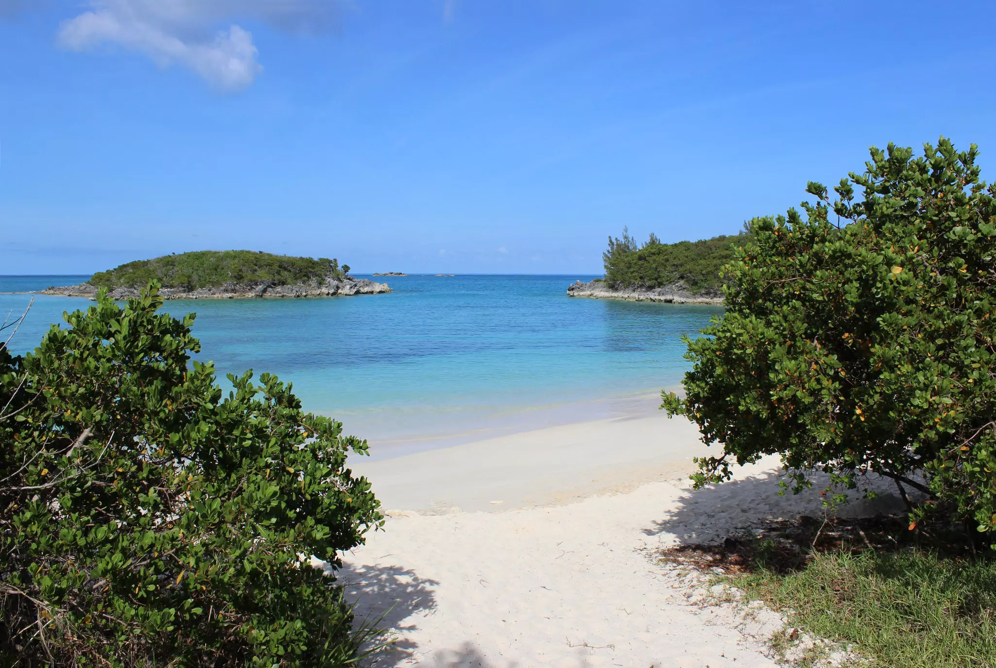A sheltered sandy cove with turquoise waters lapping at the shore.