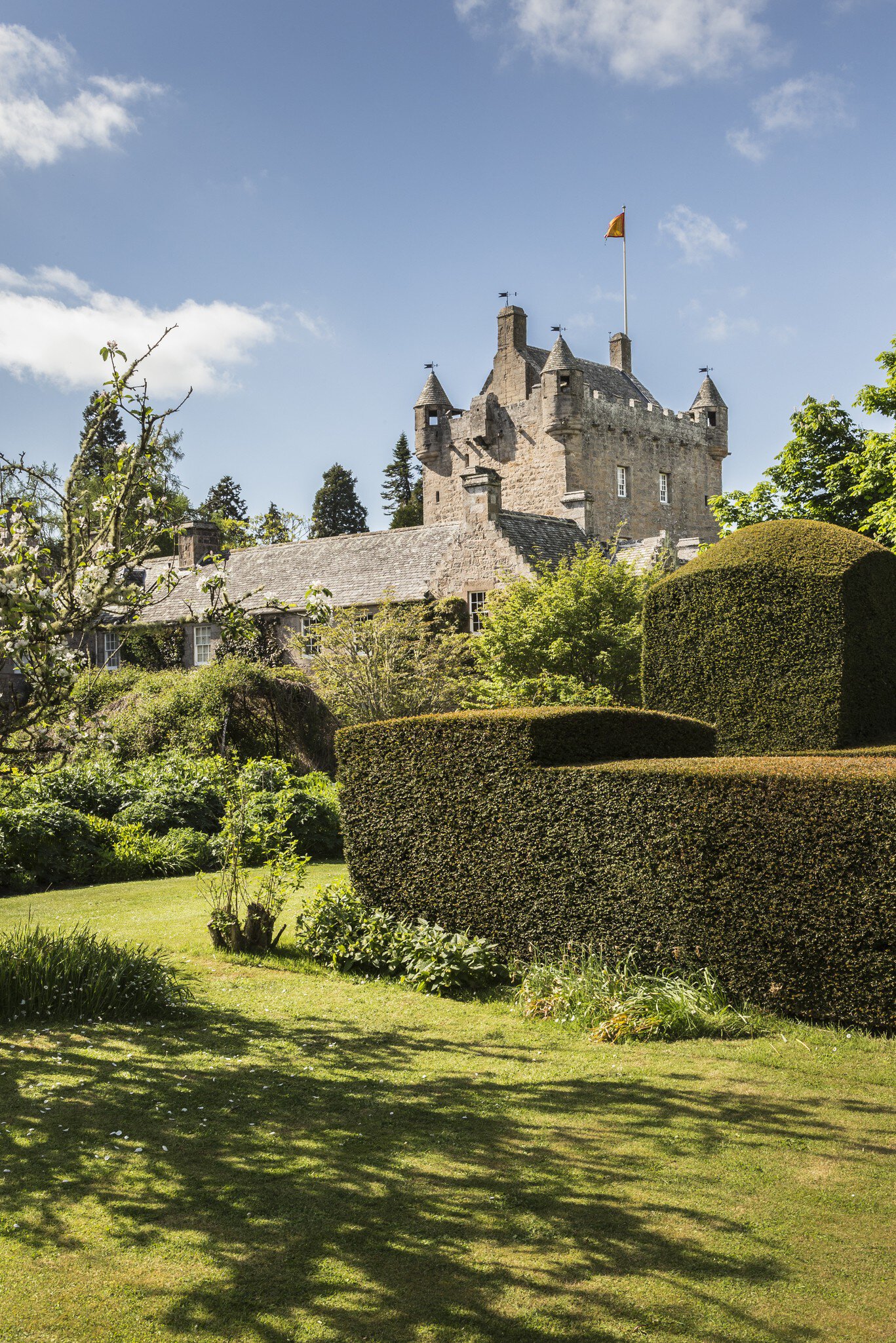 View of Cawdor Castle Gardens in Inverness-shire with blue sky and a trimmed hedge in the foreground