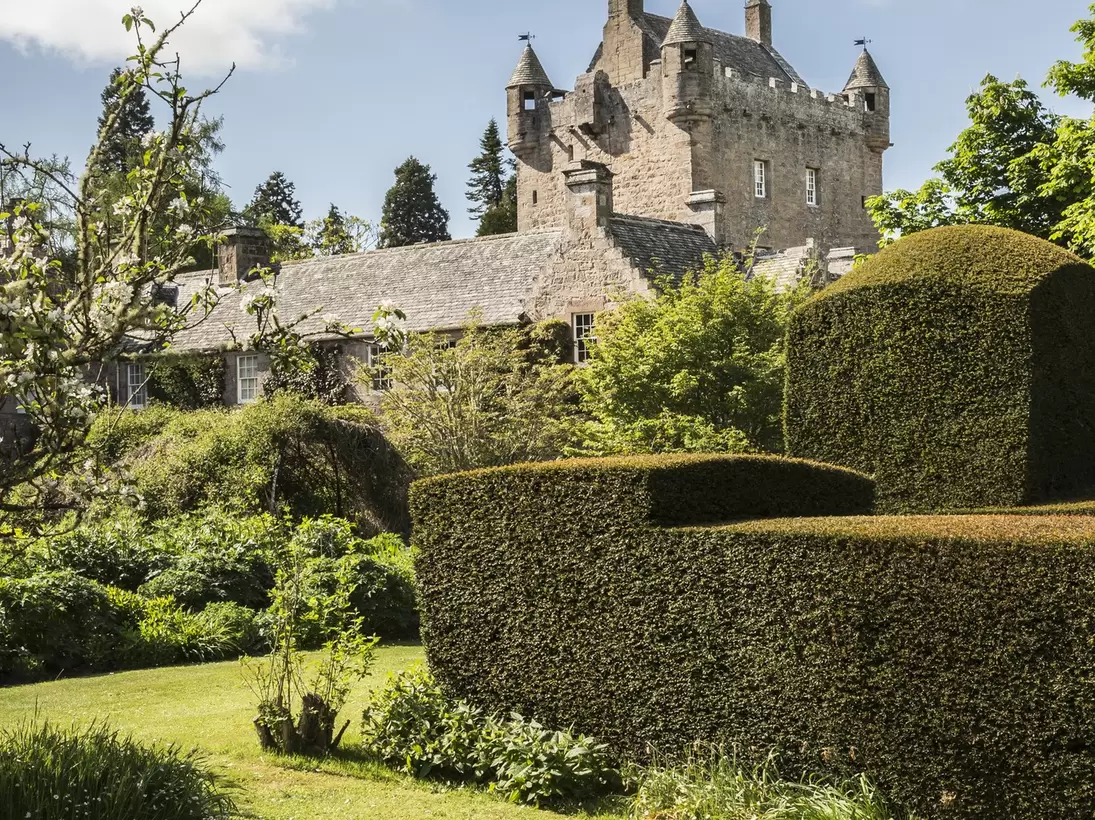 View of Cawdor Castle Gardens in Inverness-shire with blue sky and a trimmed hedge in the foreground
