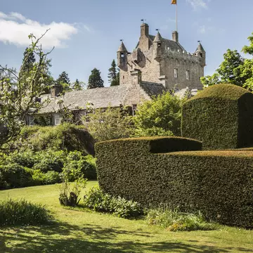 View of Cawdor Castle Gardens in Inverness-shire with blue sky and a trimmed hedge in the foreground