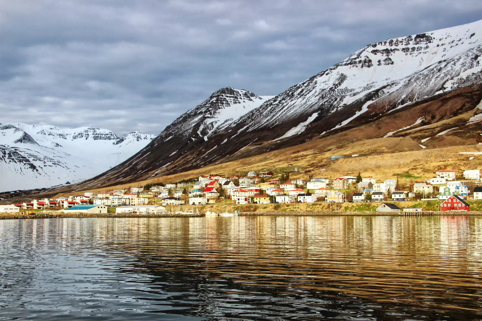 A small fishing town lined with colorful houses at the foot of snowy mountains