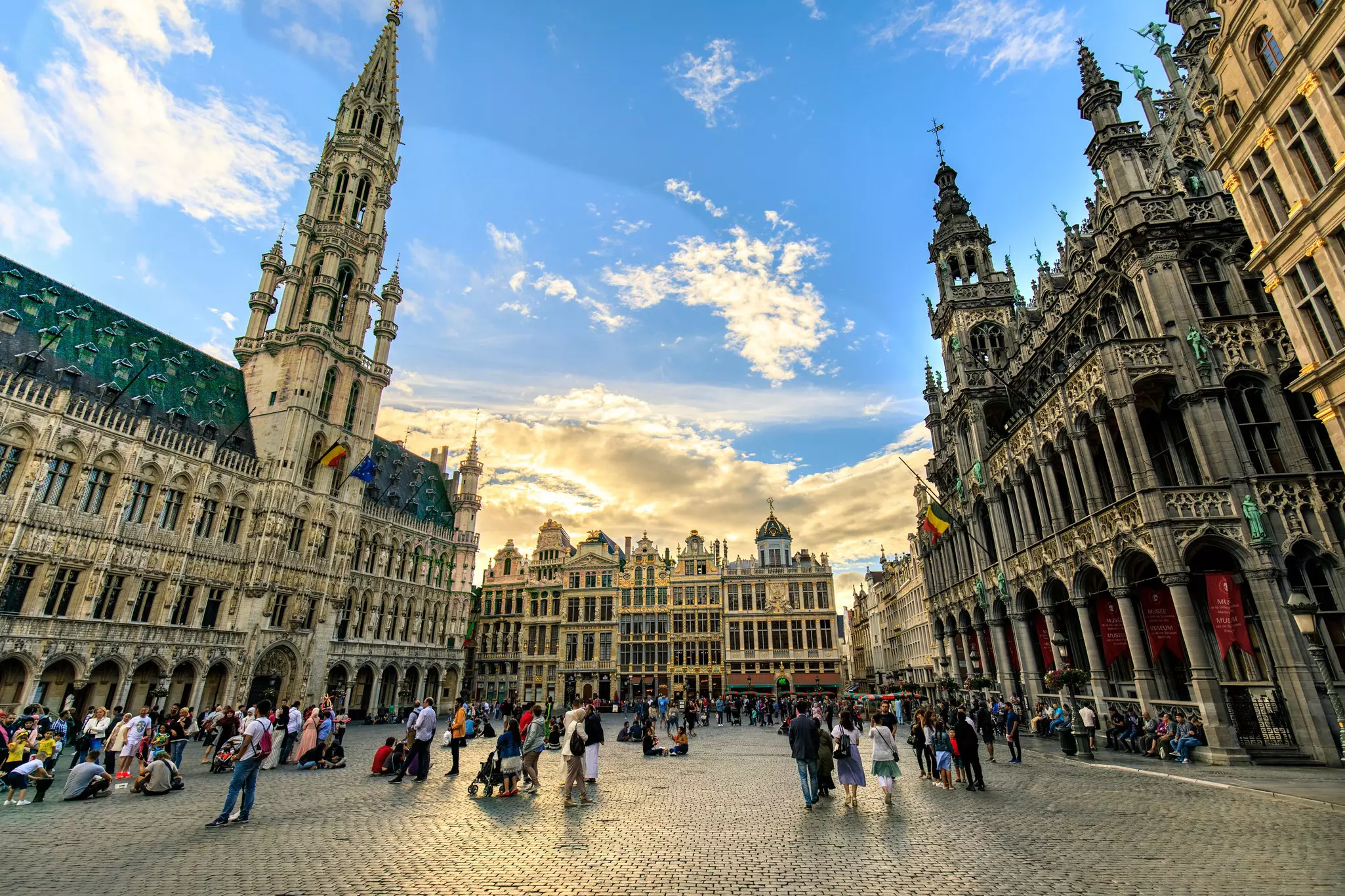 Tourists on the open square lined with grand Gothic buildings in the center of a city