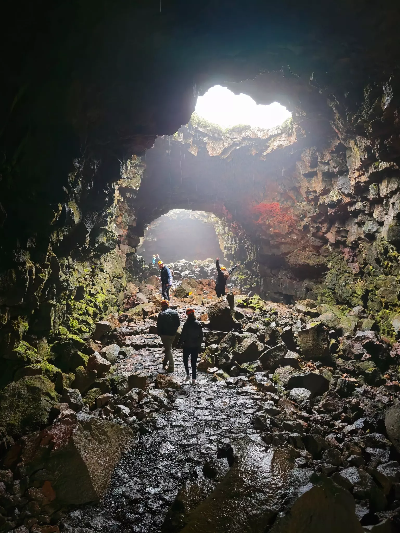 Travelers explore the lava tunnel in Raufarhólshellir, Iceland. This volcanic cave is one of the longest lava tubes in the country and a popular tourist attraction for cave tours.