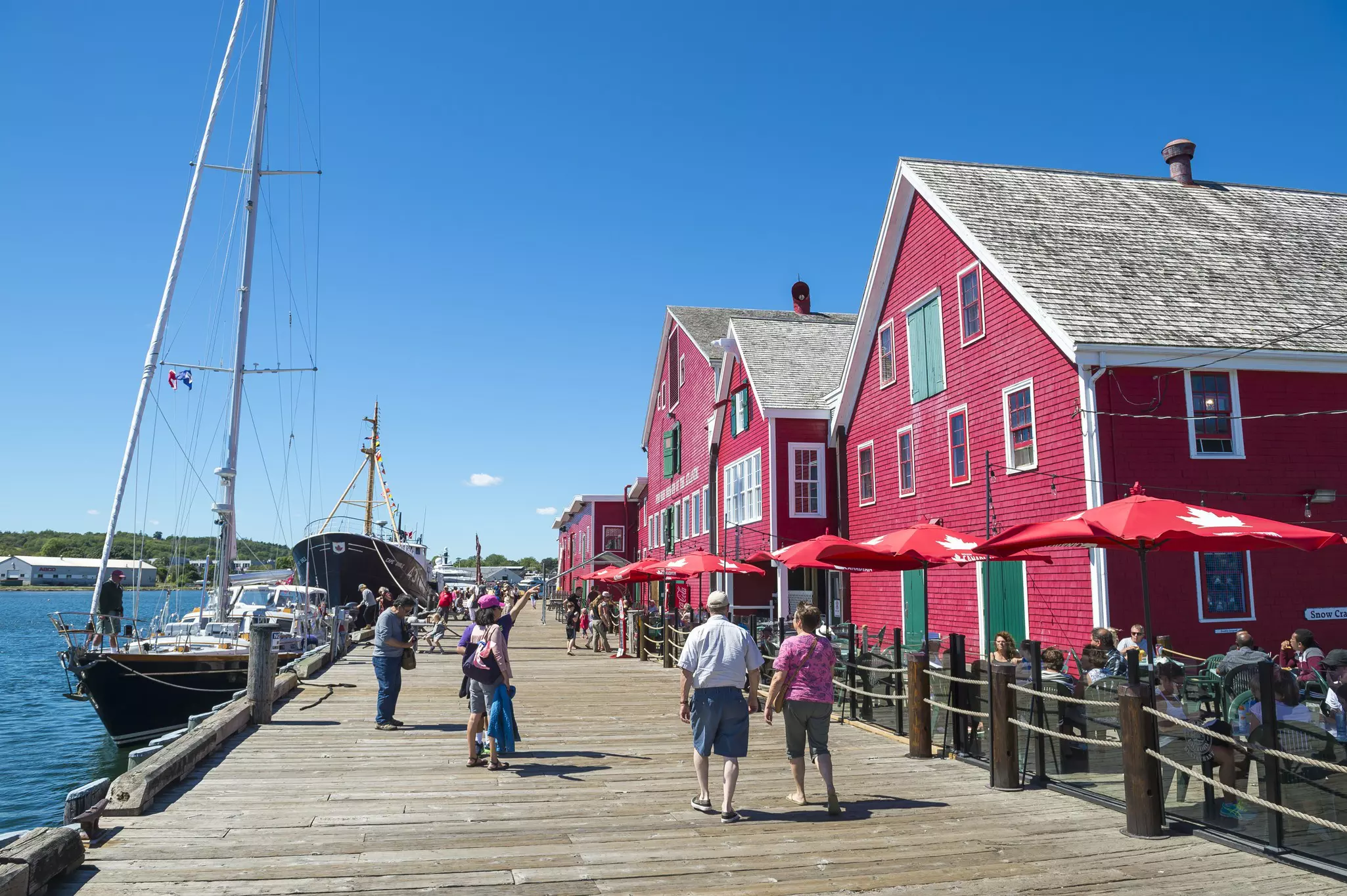 Tourists stroll along the rustic wooden boardwalk in front of the classic wooden architecture of the UNESCO World Heritage British colonial settlement.