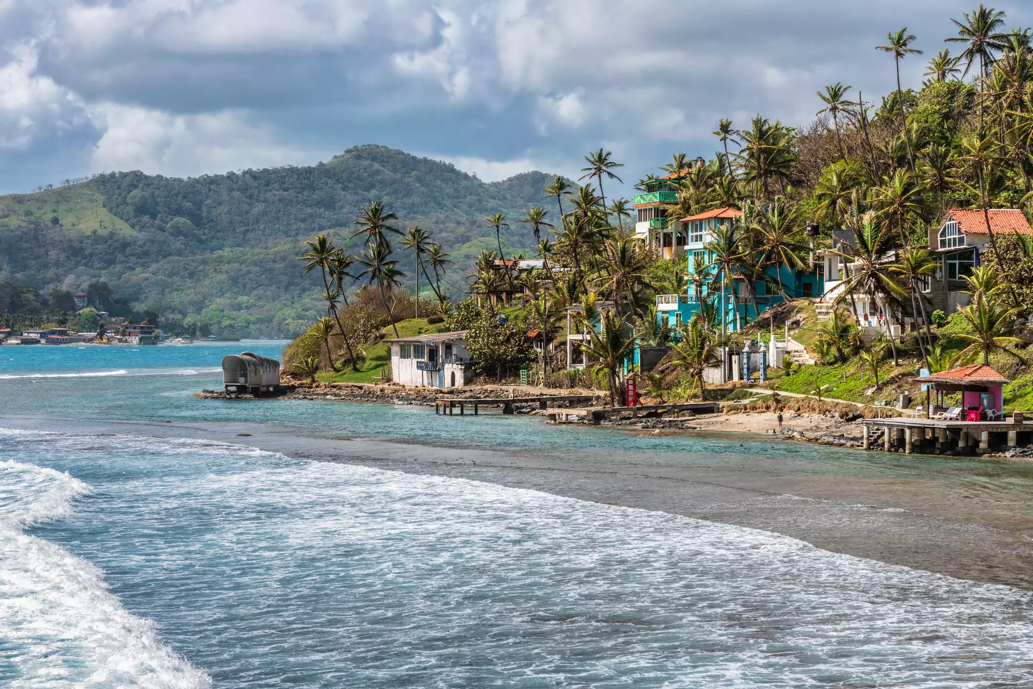 Palm trees, sea and houses on the shore of Isla Grande, Panama